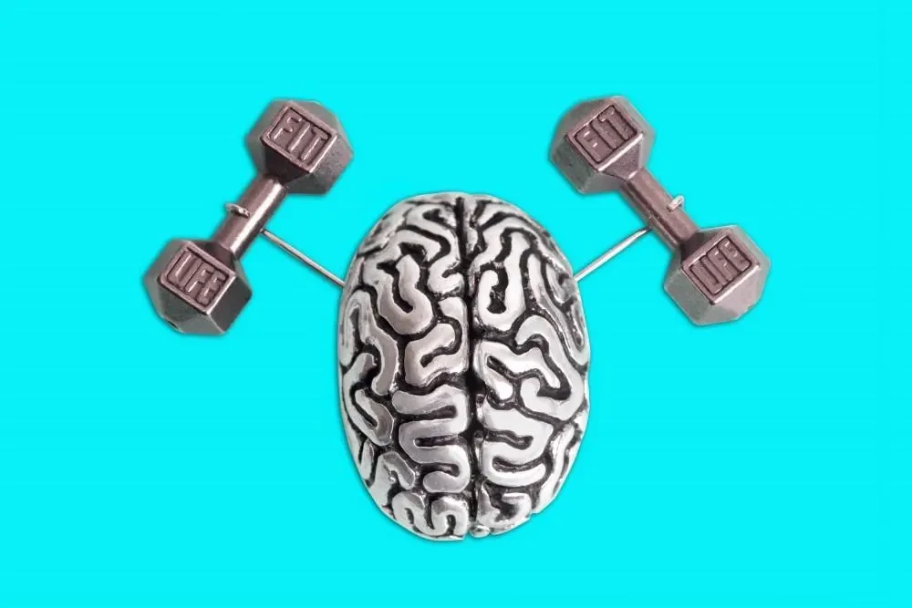 Image of a brain with two dumbbells on either side, suggesting the concept of exercising the brain. The background is turquoise.