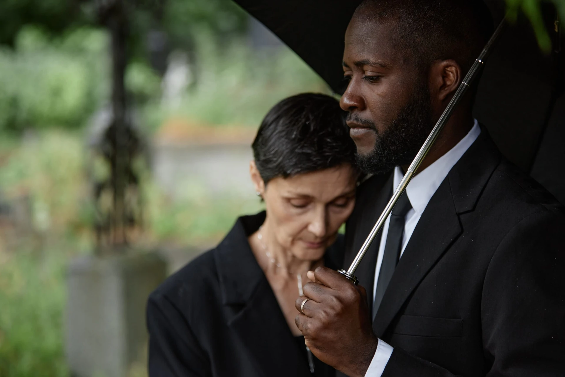 Man embracing women under black umbrella.